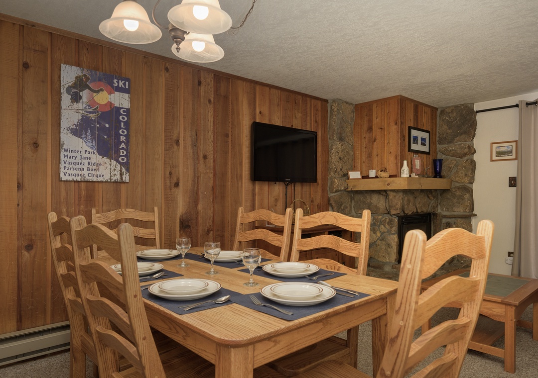 Gather around your cozy dining table, perfectly set for memorable meals beneath warm pendant lights and rustic wood paneling.