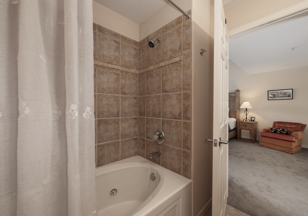 Step into your private bathroom featuring elegant tiled walls and a relaxing tub-shower combo, perfect for unwinding after exploring.