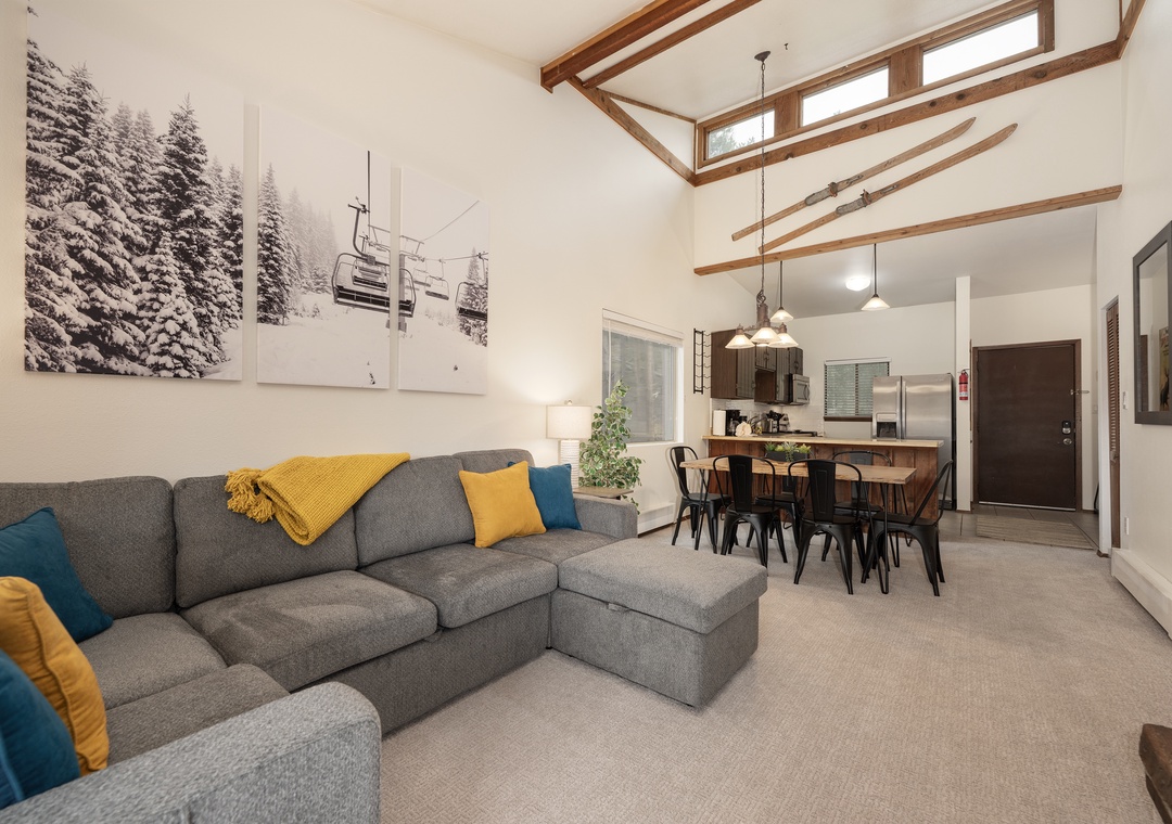 Relax in your open-concept living space with soaring wood beam ceilings and cozy sectional seating, perfect for unwinding after mountain adventures.
