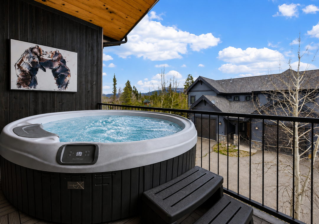 Soak away your cares in your private hot tub on the deck, surrounded by lush forest and mountain views under clear blue skies.