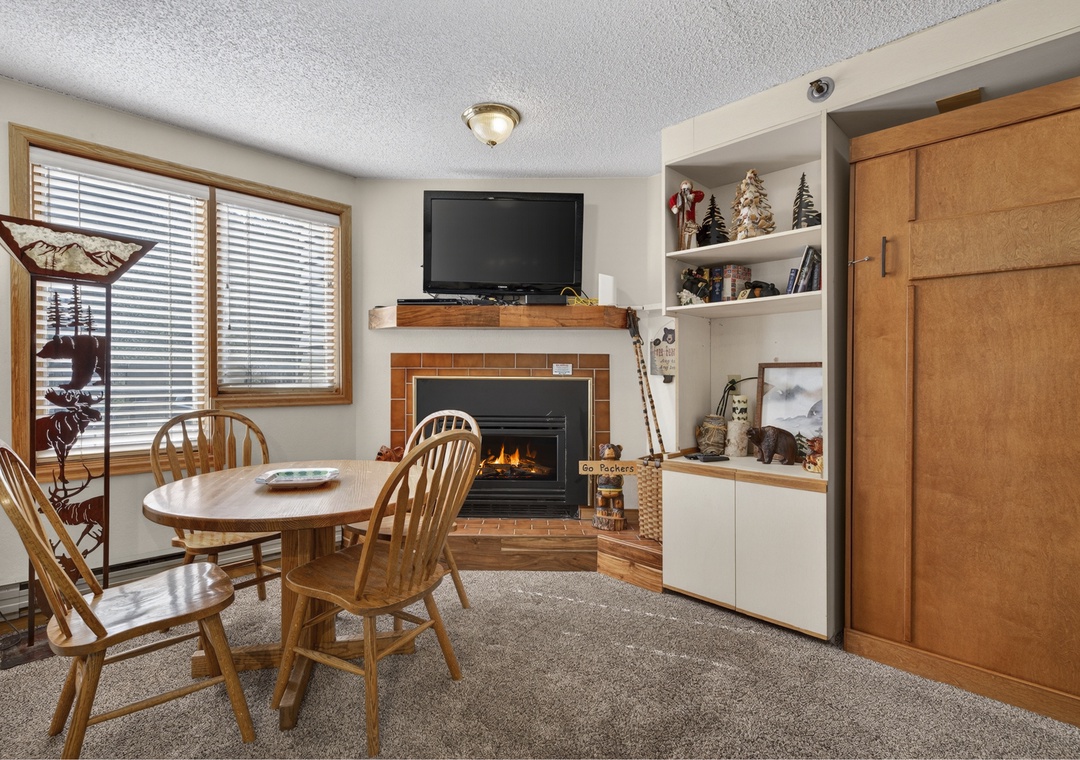 Gather around this cozy dining space where a warm fireplace sets the perfect ambiance for your meals and evening conversations, with entertainment and comfort at your fingertips.