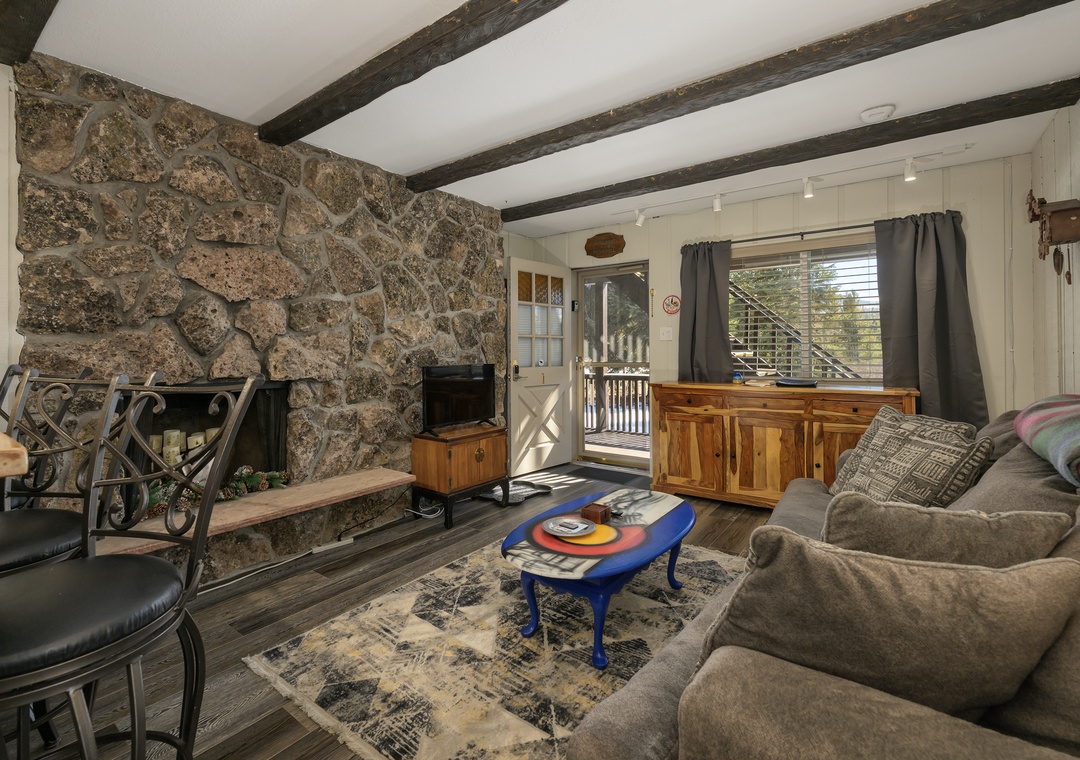 Relax by your stone fireplace while rustic beams frame cozy moments in this charming living space.