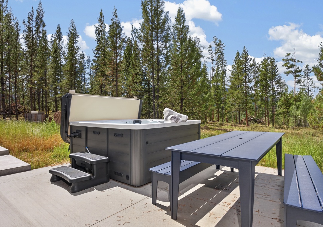 Private outdoor hot tub surrounded by towering pines and open skies—soak under the stars or enjoy the peaceful forest views from your deck.