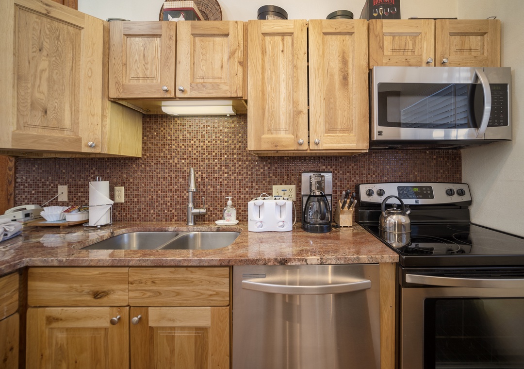 Your fully equipped kitchen features warm wood cabinets, granite counters, and modern appliances perfect for preparing meals.