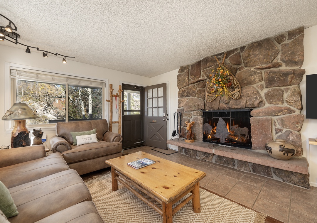 Relax in your cozy living room featuring a stunning stone fireplace and comfortable seating perfect for evening gatherings.