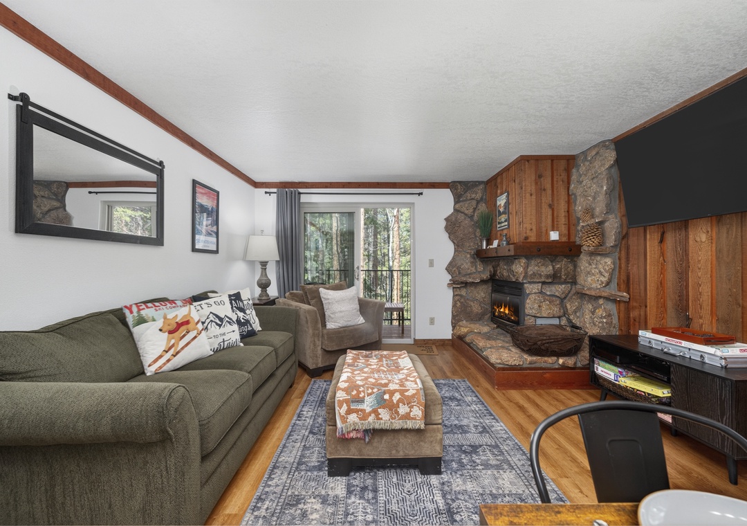 Cozy up by your crackling stone fireplace in this inviting living room, where warm wood accents and comfortable seating create the perfect mountain retreat atmosphere.