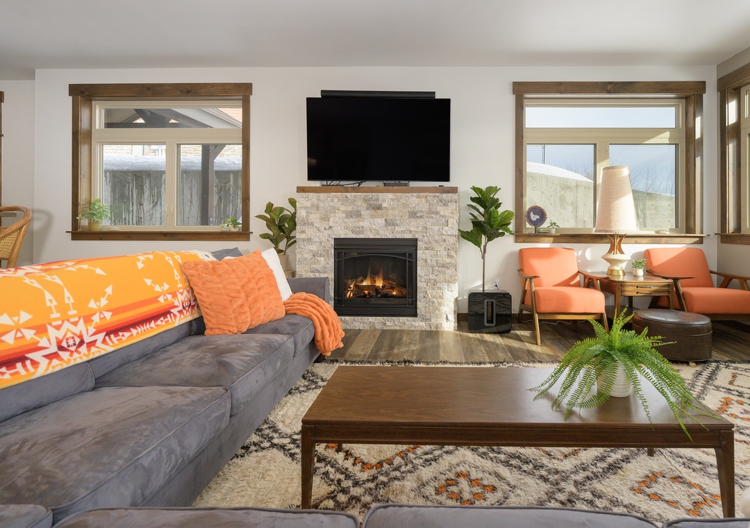 Cozy up by your stone fireplace in this bright living space with plush seating and warm natural light streaming through oversized windows.