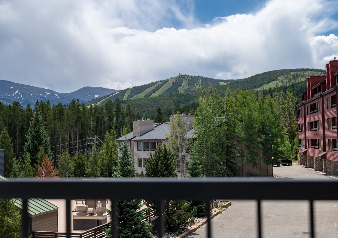 Mountain views and ski slopes frame this peaceful alpine setting surrounded by forest and residential buildings.