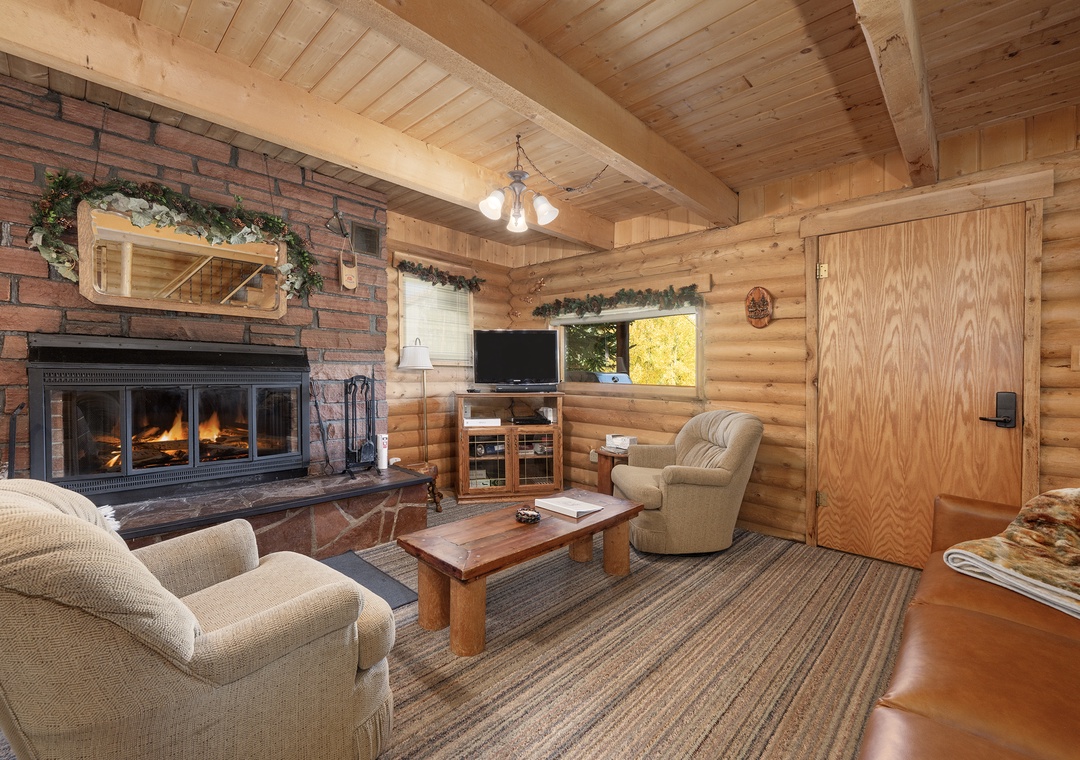 Cozy up in your rustic living room with crackling fireplace, exposed wood beams, and comfortable seating perfect for mountain evenings.