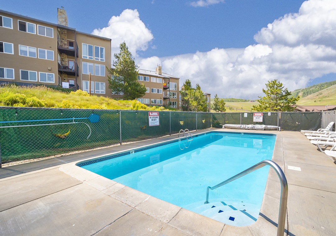The communal pool and tennis court are set against a backdrop of rolling hillsides and mountain views, surrounded by mature greenery and ample sun loungers for your relaxation.