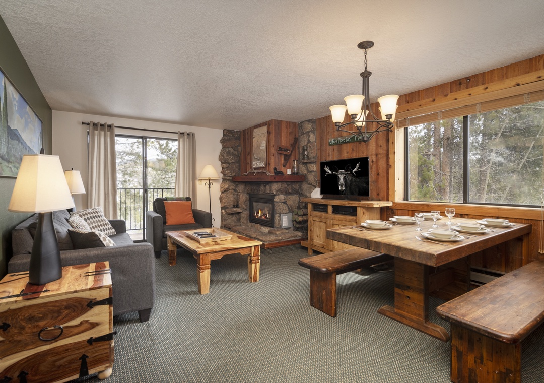 Cozy up in your rustic mountain retreat with a stone fireplace, rustic dining nook, and forest views through expansive windows.