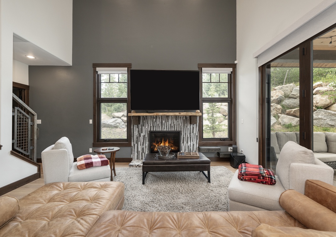 Unwind in this stylish living room where you can cozy up by the fireplace with plaid throws and enjoy mountain views.