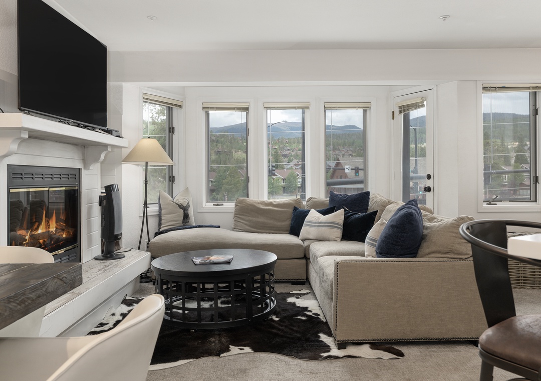 Sink into plush sectional seating by your crackling fireplace while mountain views frame your perfect retreat through panoramic windows.