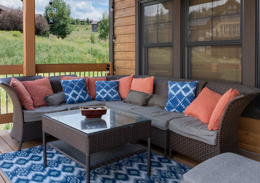 Sink into plush outdoor seating with vibrant pillows on your private deck, where morning coffee meets mountain meadow views.