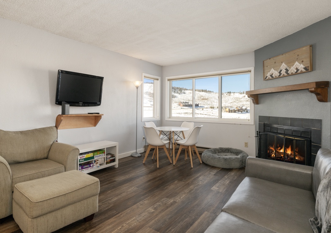 Cozy up by your crackling fireplace at Summit Unit 1103 while gazing at snowy mountain views through large windows in this inviting living space.