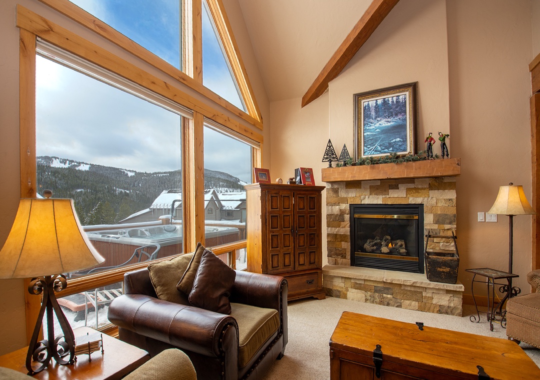 Cozy up by your crackling fireplace while enjoying mountain views through floor-to-ceiling windows in this warm living room.