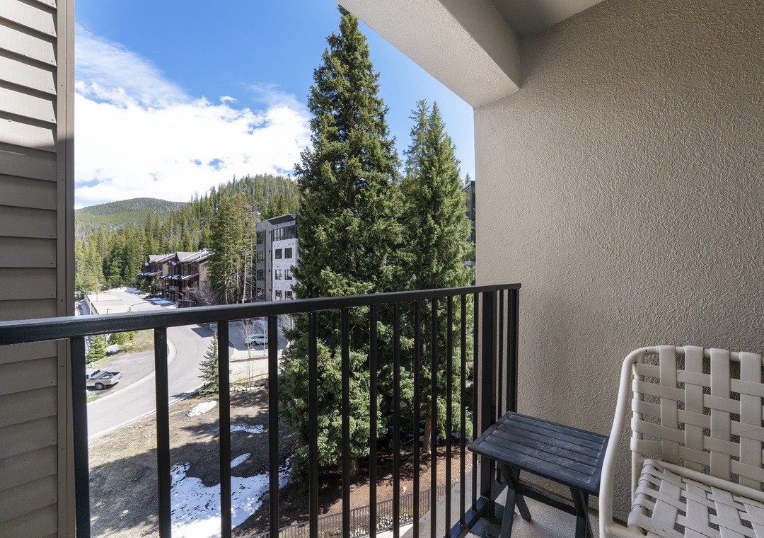 Step onto your private balcony and breathe in the crisp mountain air as you take in views of towering pines, nearby buildings, and tree-lined streets below.