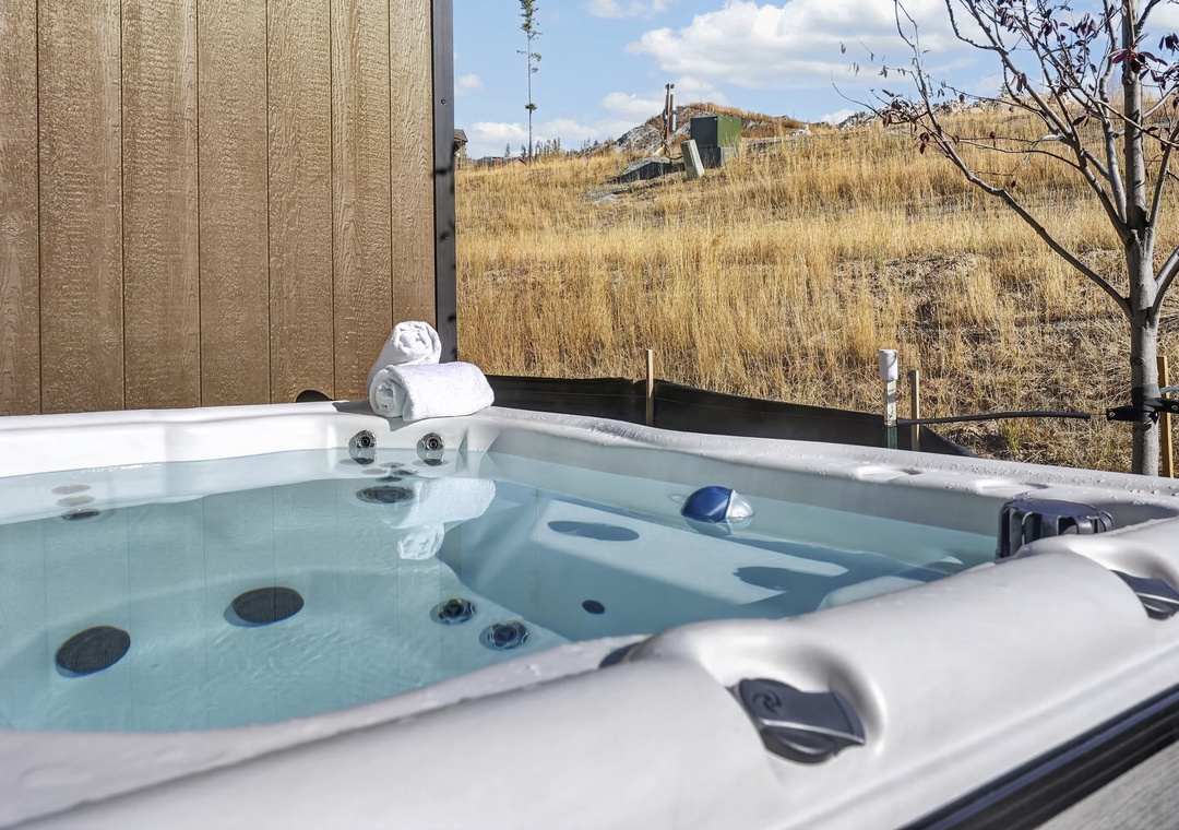 Soak in your private hot tub and gaze out at the wide-open landscape—pure relaxation under blue skies and endless prairie views.