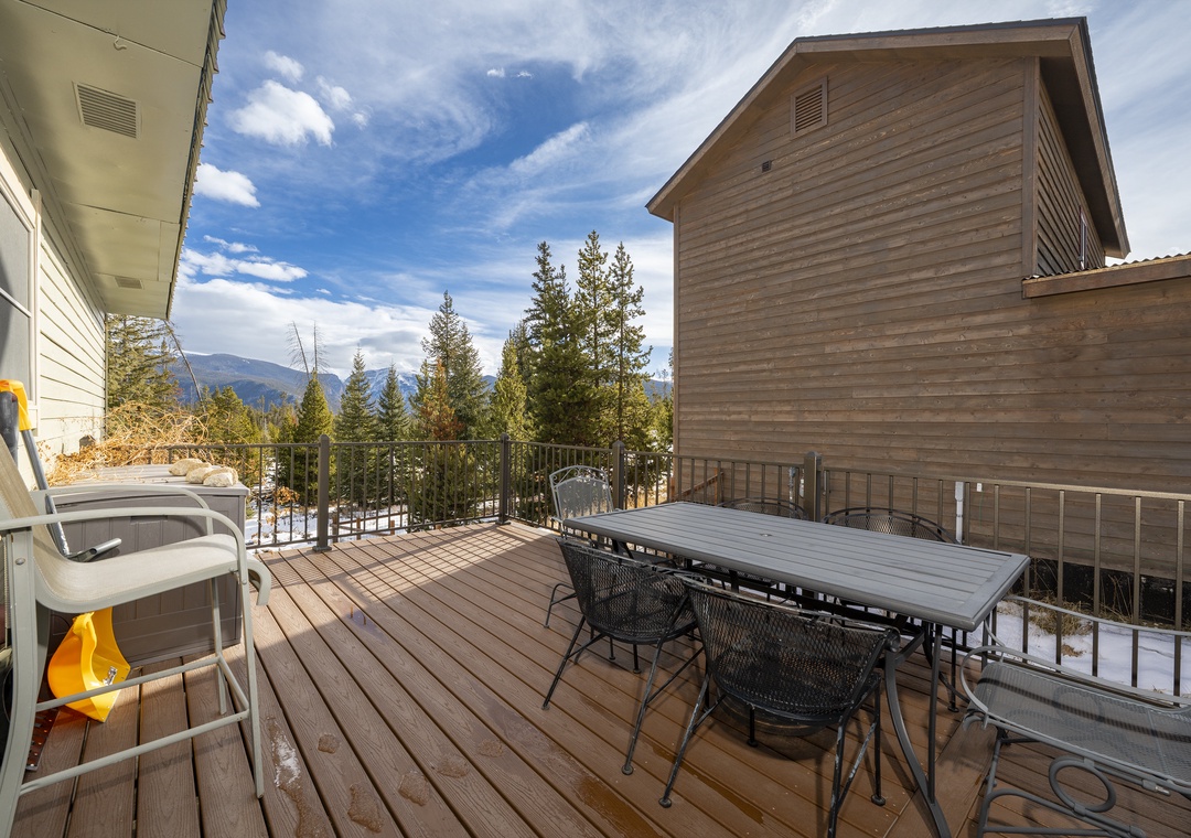 Expansive deck at 874 Kinnikinnick Road has outdoor dining and breathtaking mountain views surrounded by evergreen forest.