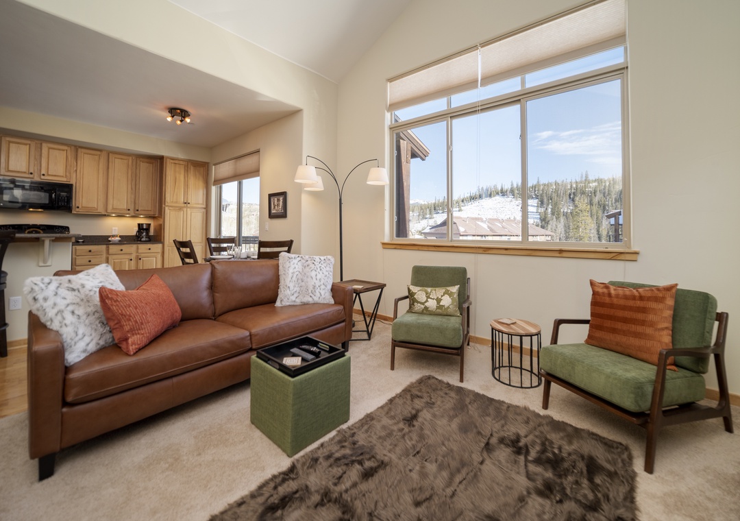 Relax in your cozy living room with plush leather seating and stunning mountain views through expansive windows.