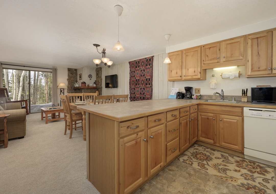Your spacious kitchen features warm wood cabinets and flows into the cozy living area with peaceful forest views.