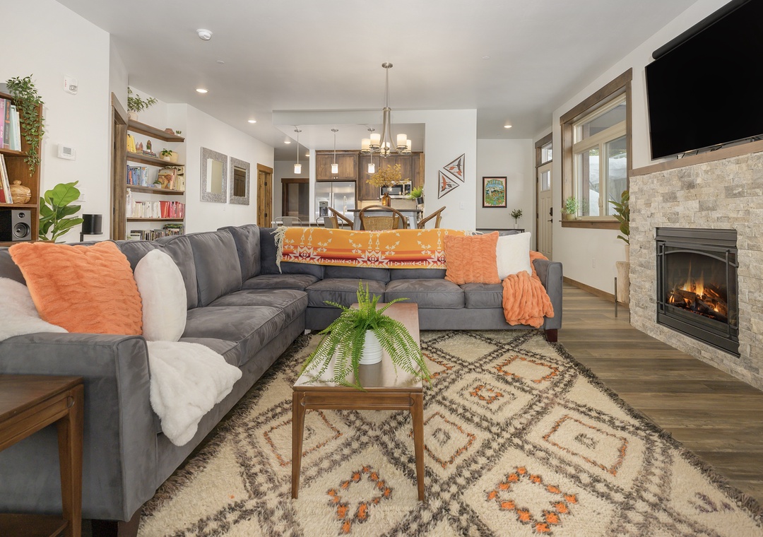 Sink into plush sectional seating while the stone fireplace crackles nearby, creating your perfect evening retreat in this open-concept living space.
