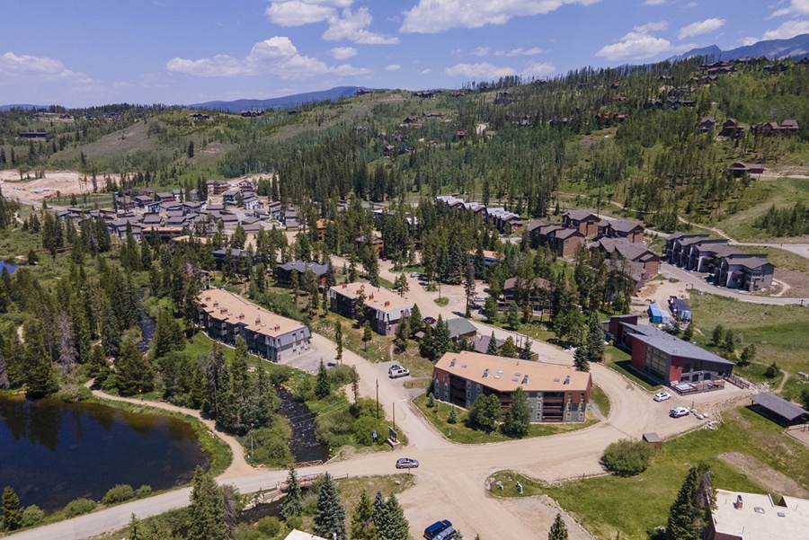 An aerial overview of the property nestled among evergreens and rolling hillsides, showcasing the mountain setting and surrounding natural beauty.