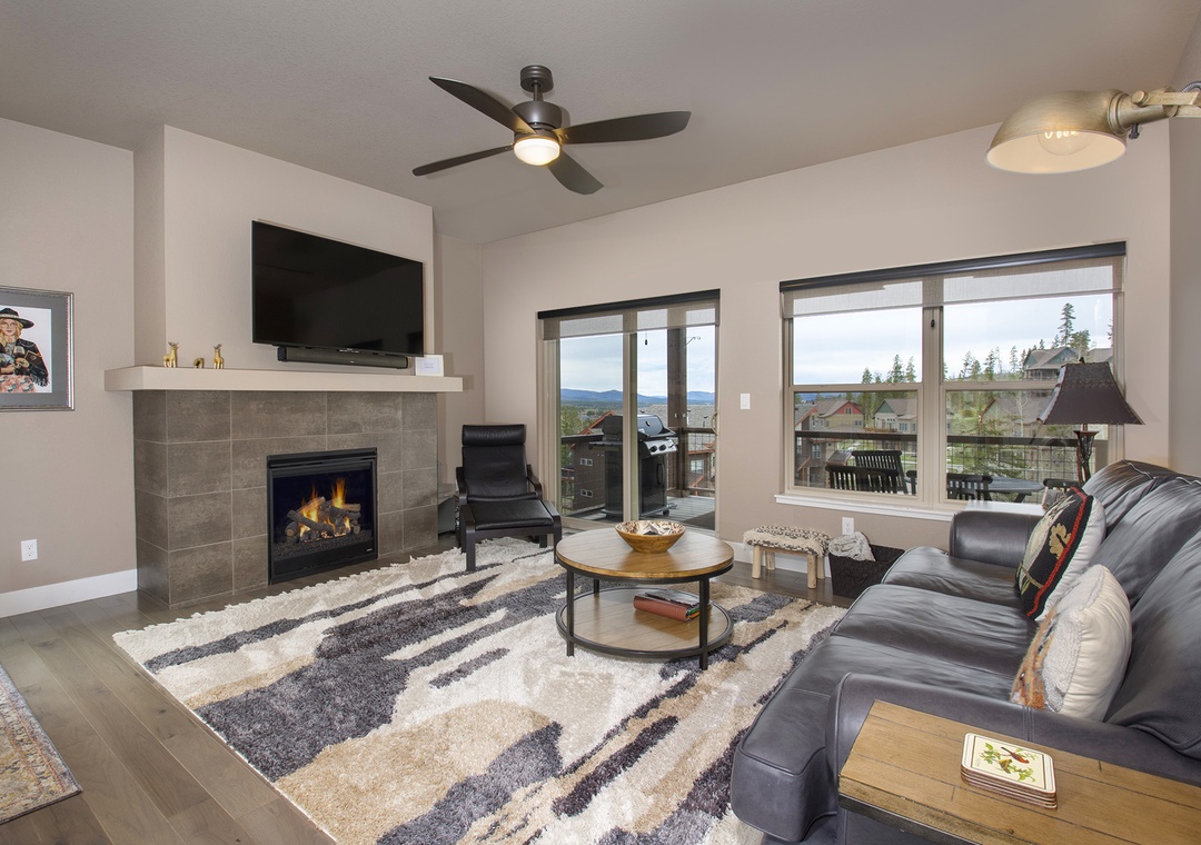 Unwind in your spacious living room with crackling fireplace, plush leather seating, and stunning mountain views through floor-to-ceiling windows.
