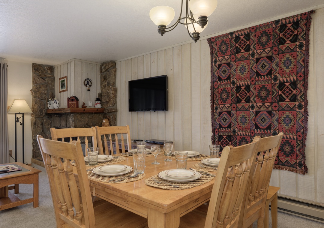 Gather around your rustic dining table for memorable meals, with charming stone fireplace and warm décor creating the perfect mountain retreat atmosphere.