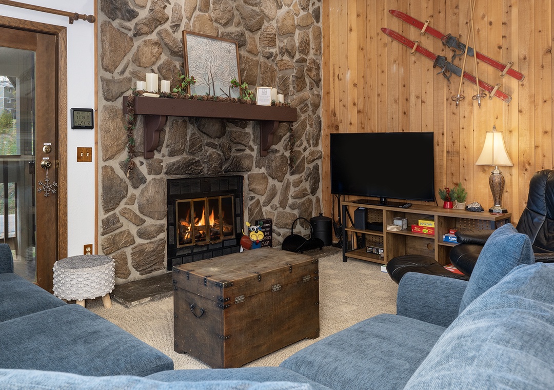 Cozy up by your crackling stone fireplace while watching TV on plush blue sofas in this warm mountain retreat.