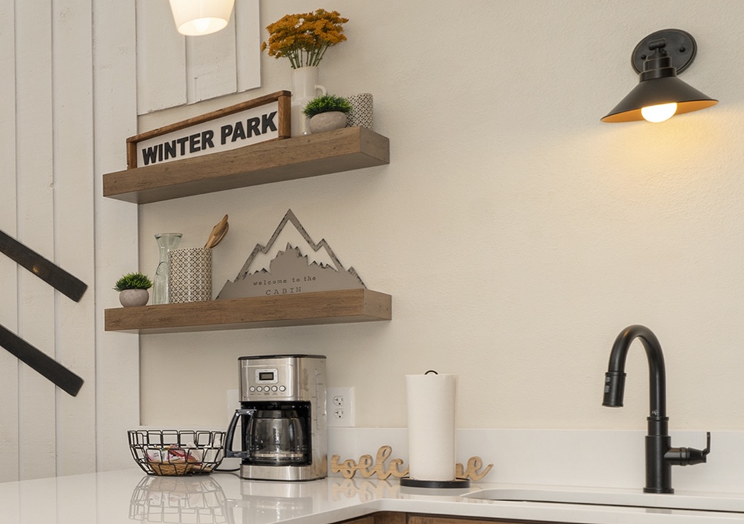 Start your mornings with freshly brewed coffee in this stylish kitchen corner, complete with charming mountain-themed decor and rustic floating shelves.