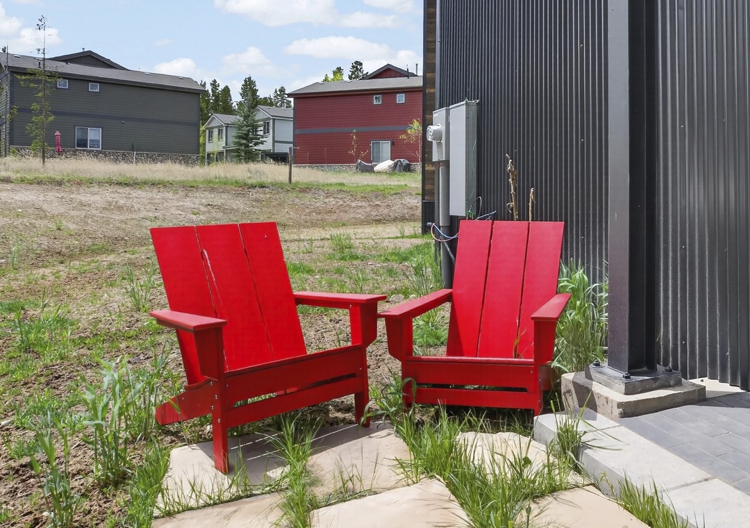 A modern vacation property located in a peaceful residential setting, offering a quiet retreat with contemporary dark exterior architecture and vibrant outdoor seating near the entrance.
