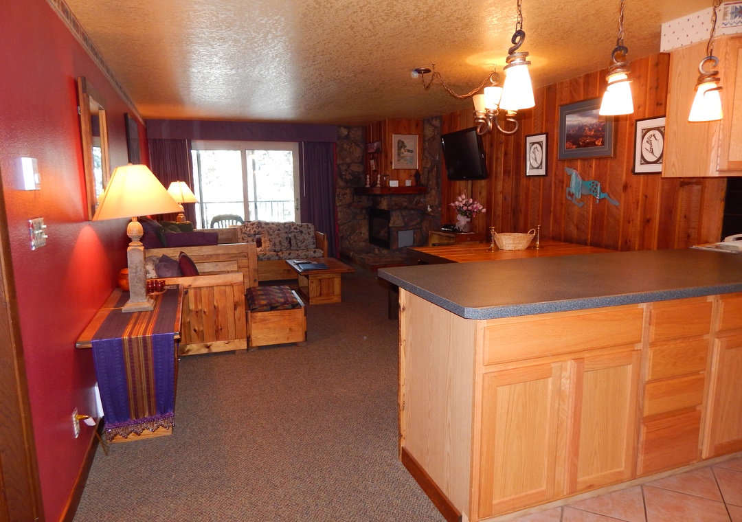 Cozy mountain retreat with warm wood touches, stone fireplace, and open kitchen - your perfect ski lodge escape awaits.