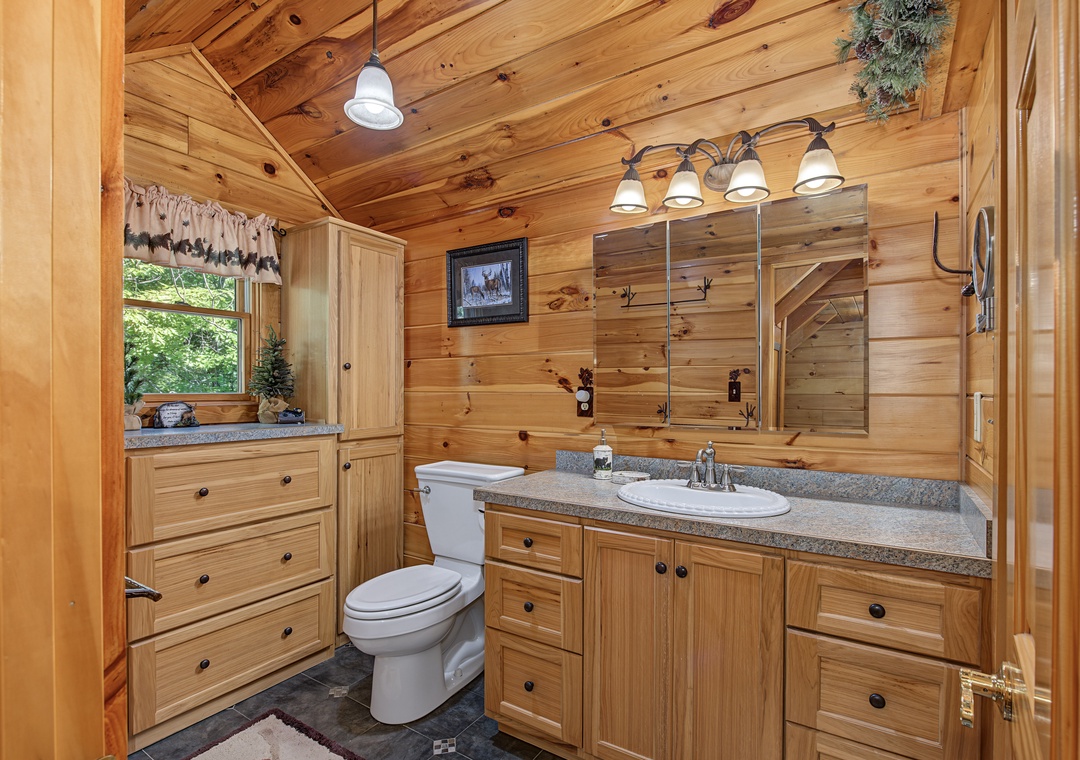 Step into your private cabin-style bathroom, where warm wood surrounds you and natural light streams through the window. Freshen up at the spacious vanity before your next mountain adventure.