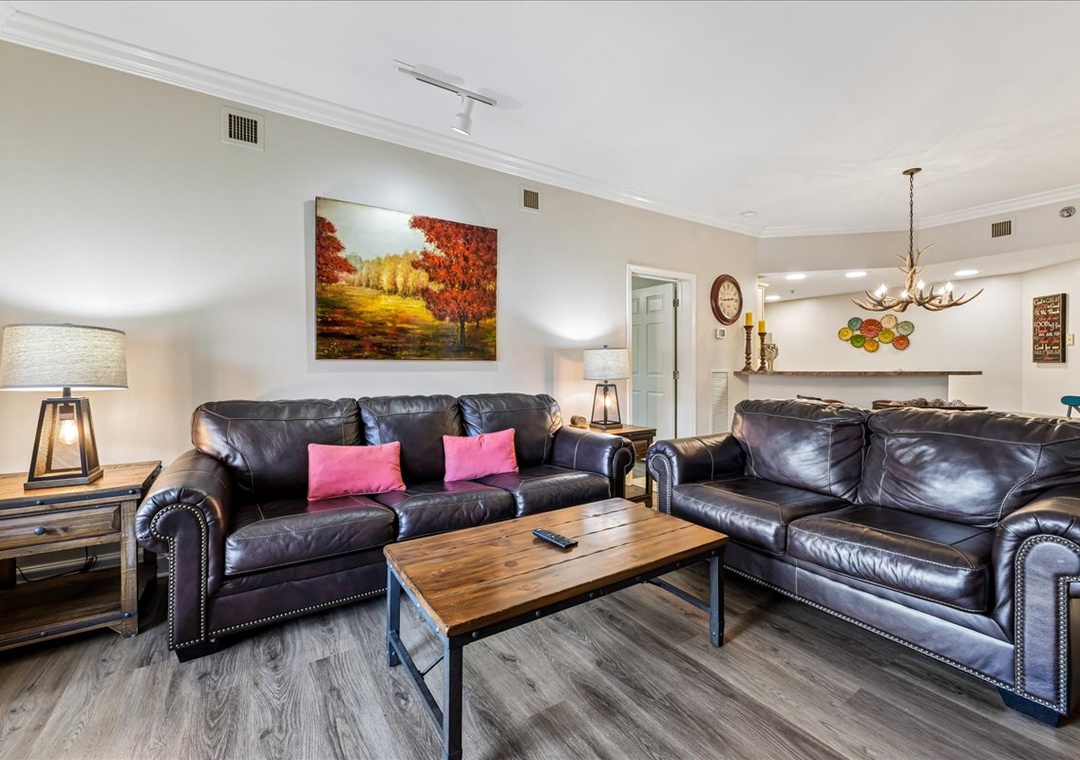 Sink into plush leather sofas in your spacious living room, where warm lighting and autumn artwork create the perfect atmosphere for relaxing evenings together.