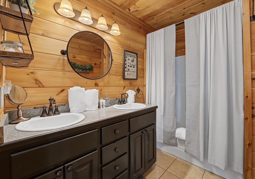 Rustic charm meets modern comfort in this beautifully appointed bathroom. Dual sinks, warm wood paneling, and soft lighting create your perfect retreat after a day of adventure.