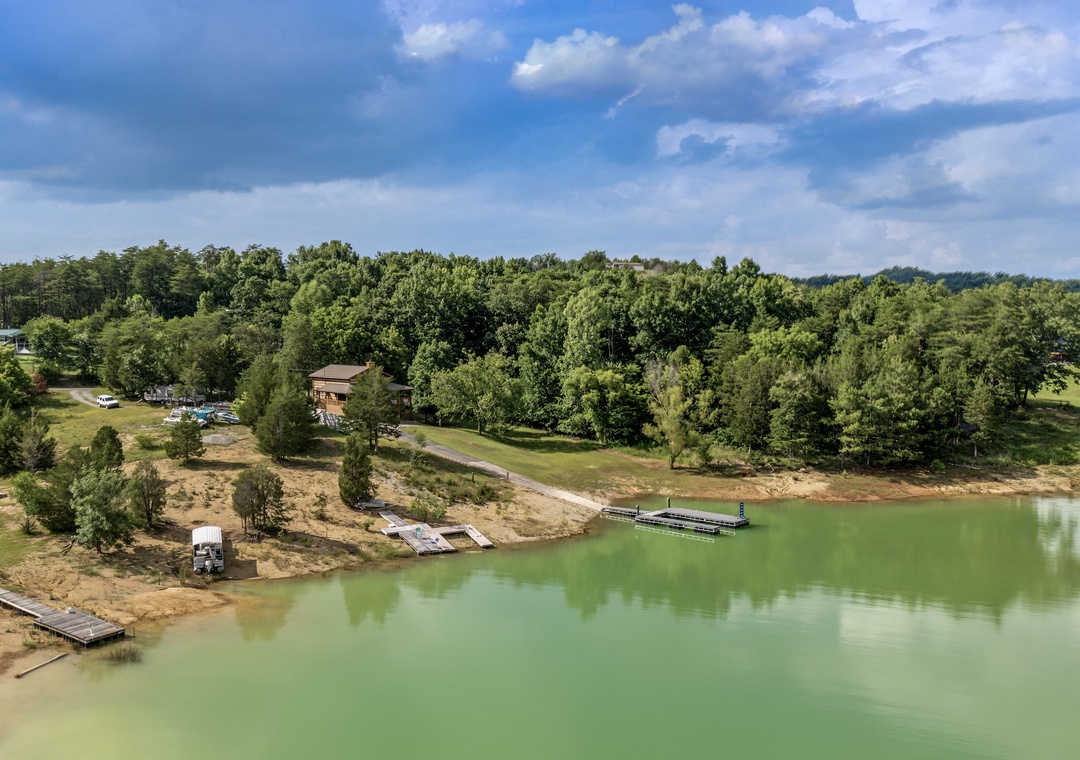 Aerial view of the property nestled along a serene lake, surrounded by lush woodlands and offering peaceful waterfront access with private docks and scenic natural beauty.