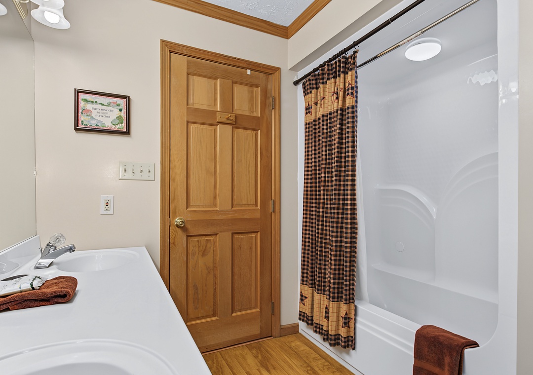 Your private bathroom features a full tub-shower combo, clean white fixtures, and warm wood accents, complete with soft towels ready for your stay.