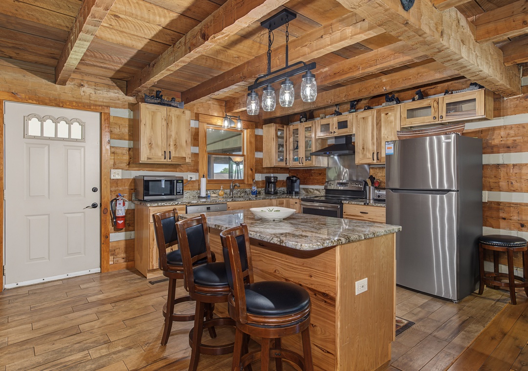 Your fully equipped cabin kitchen has everything you need, from granite countertops and modern appliances to a cozy island with bar seating—perfect for morning coffee or meal prep together.