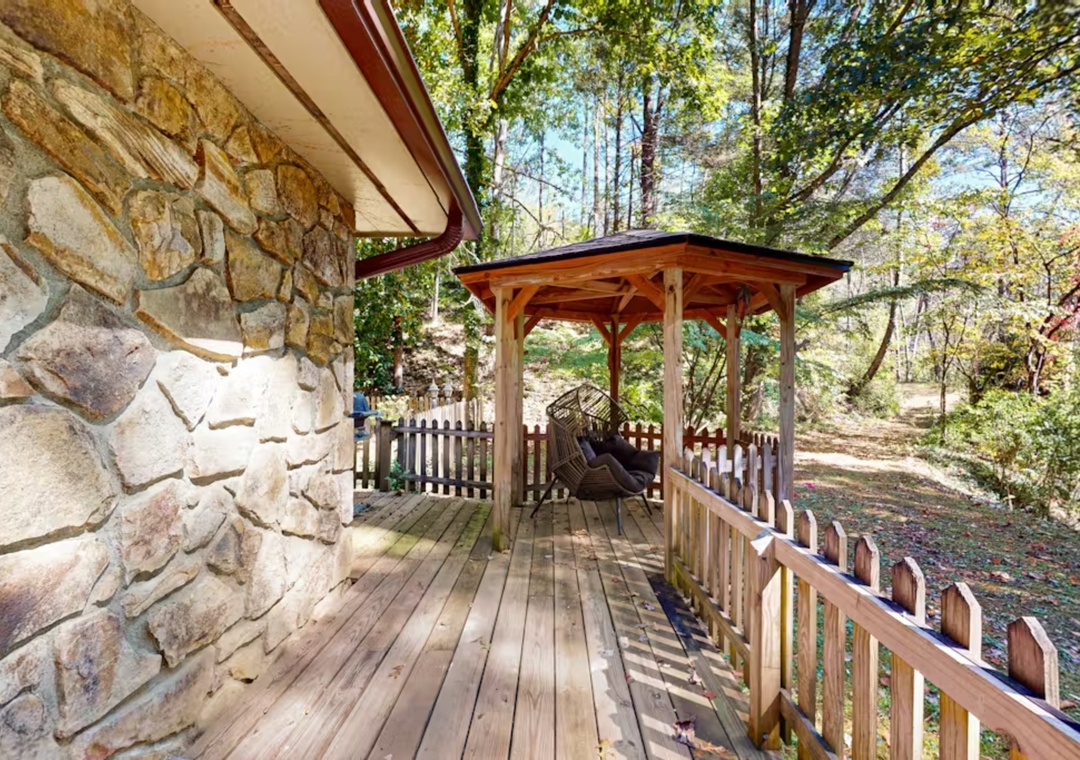 Step onto your private wooden deck, where rustic stone walls meet forest tranquility and a charming gazebo beckons for peaceful moments.