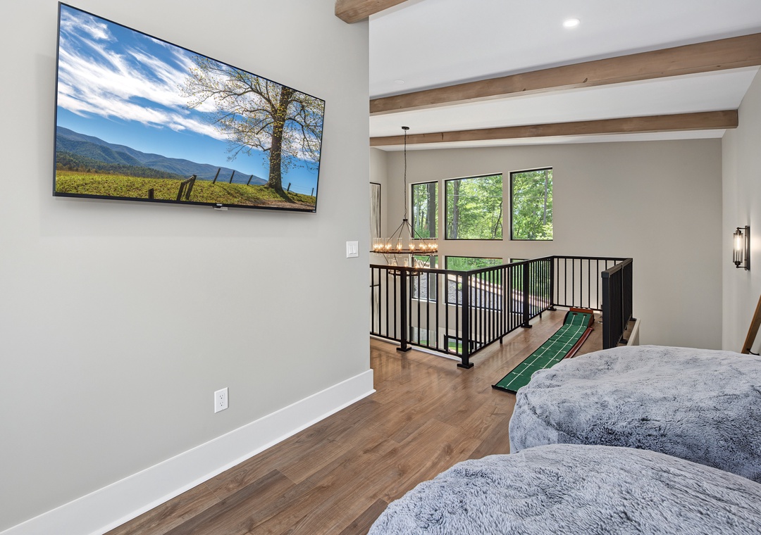 Settle into this open loft space where exposed beams meet modern comfort. Your personal retreat features a large TV, cozy seating, and natural light streaming through forest views.