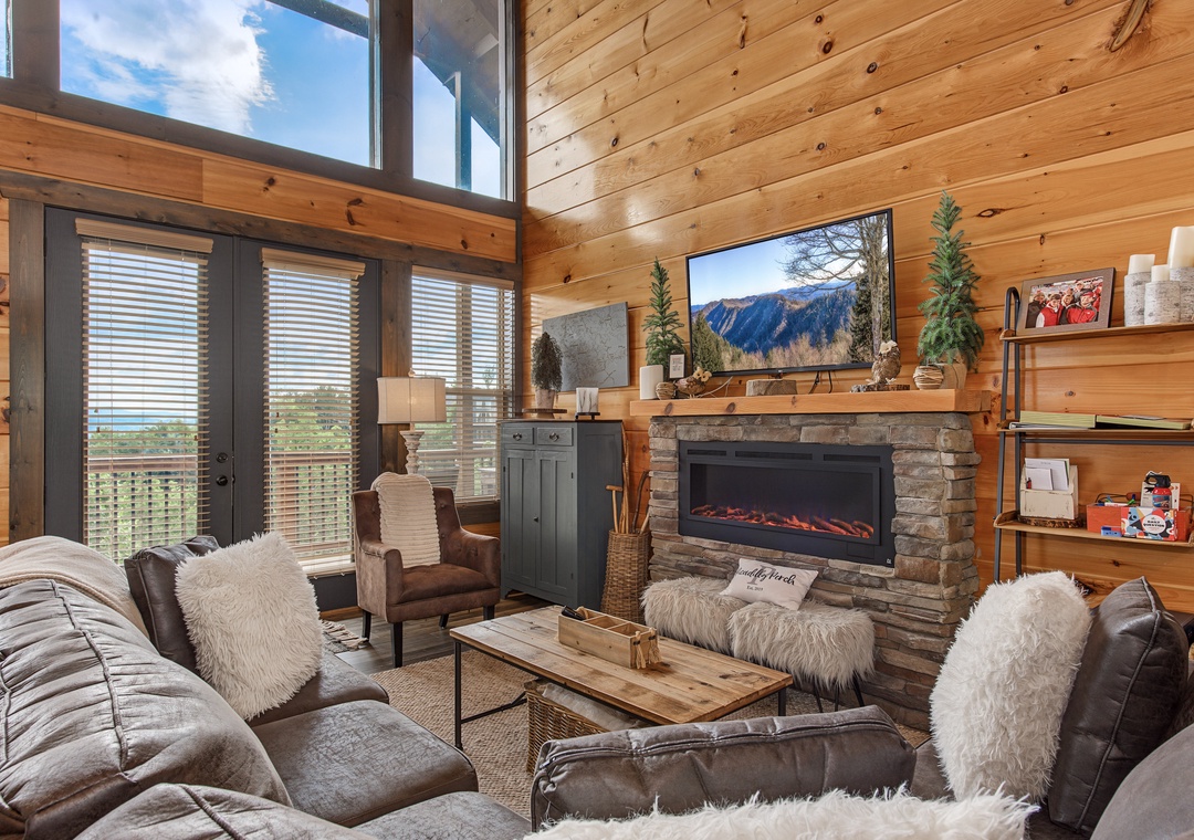 Imagine yourself sinking into plush seating by a crackling fireplace, mountain views framing your relaxation in this bright, airy cabin-style living room with soaring windows and natural warmth.