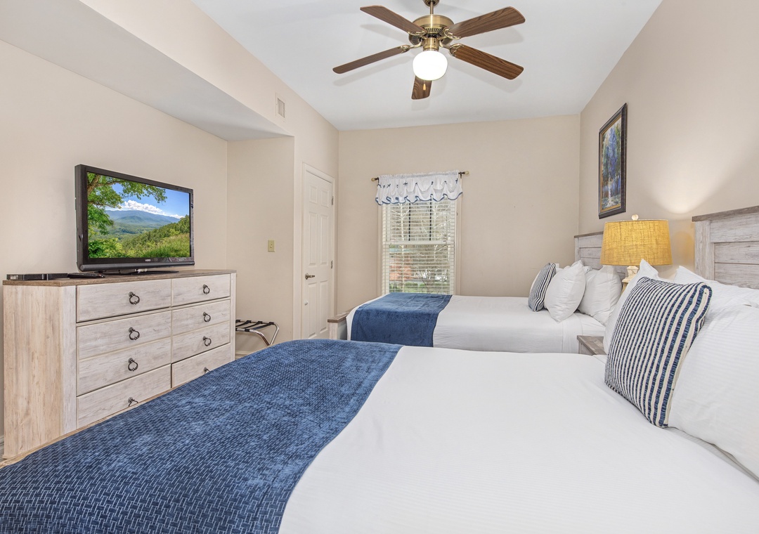 Relax in your comfortable twin bedroom with coastal-inspired blue accents, modern amenities, and a peaceful mountain view outside your window.
