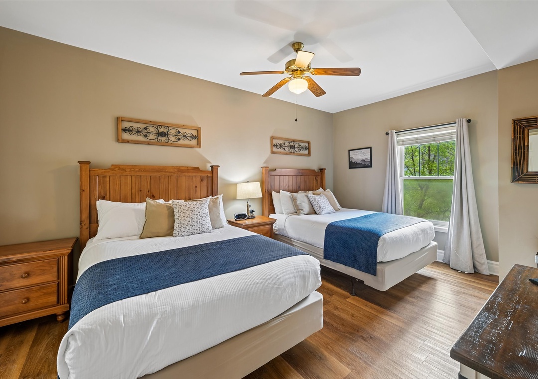Relax in your spacious bedroom with two cozy beds, warm wood accents, and peaceful garden views through your private window.