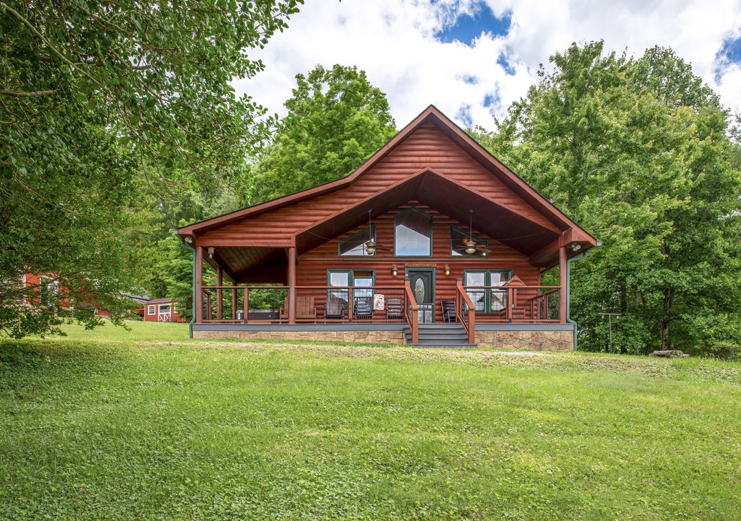 A charming log cabin nestled in lush greenery, offering a peaceful retreat with a spacious wraparound porch perfect for morning coffee and evening relaxation surrounded by nature.