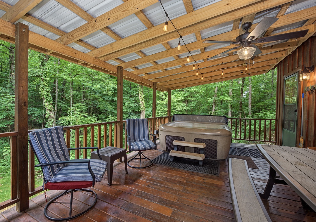 Picture yourself unwinding here—your private covered deck offers string lights overhead, a bubbling hot tub, and peaceful forest views surrounding you on all sides.