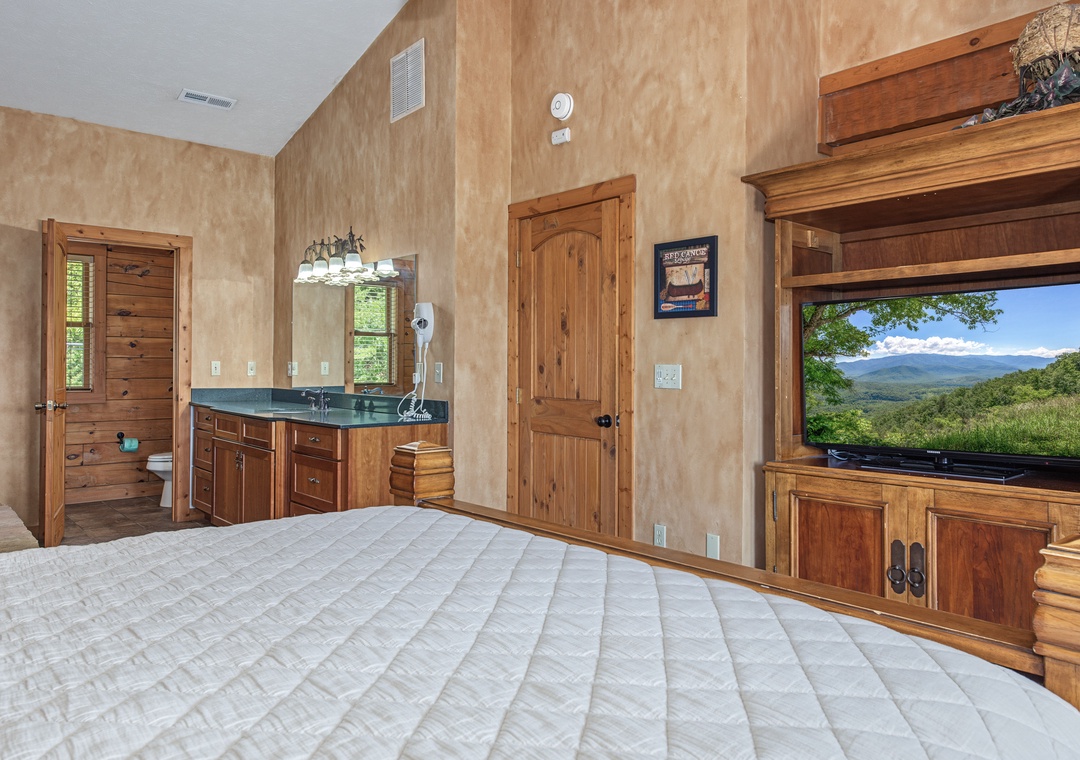 Unwind in your spacious bedroom featuring handcrafted wood furnishings, plush bedding, and stunning mountain views through the windows—your perfect retreat after a day of adventure.