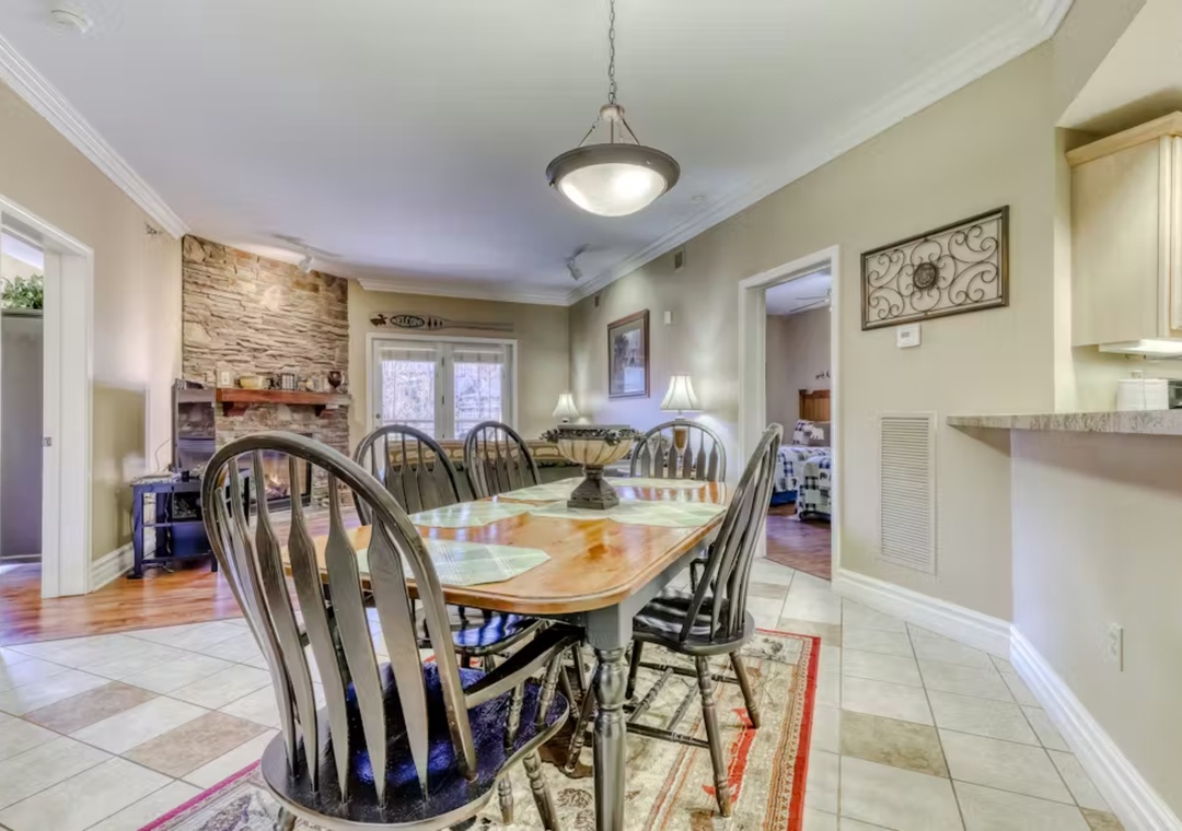 Gather around this spacious dining table where memorable meals await, featuring elegant stone accents and seamless flow to your fully equipped kitchen.