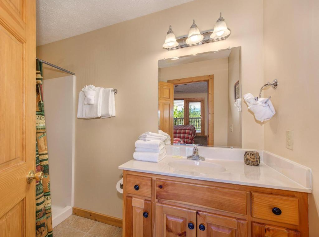 Your bright bathroom features warm wood vanity, fresh towels, and elegant lighting—perfect for your morning routine.