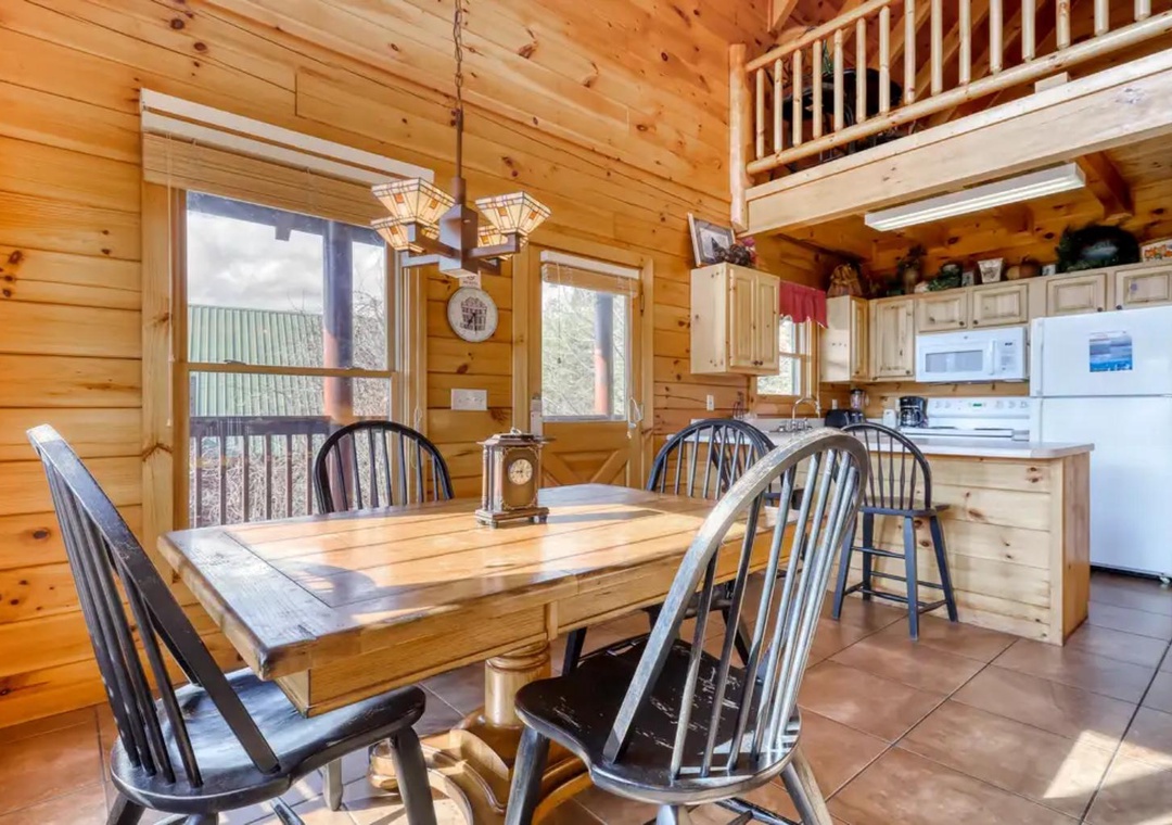 Gather around your rustic dining table in this warm cabin where natural light pours through large windows. The full kitchen awaits your favorite meals, while the cozy loft above adds mountain charm.